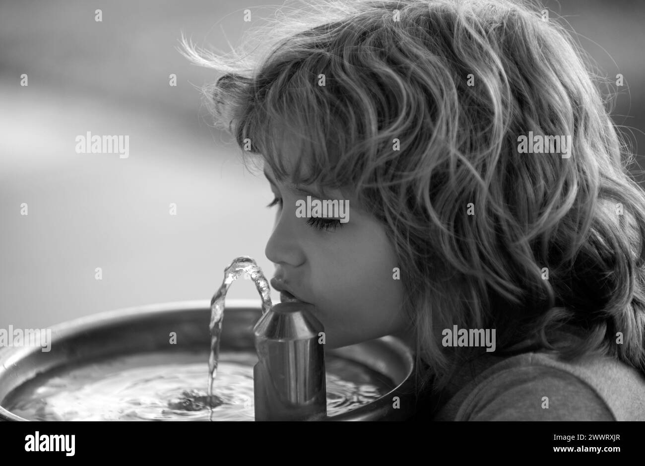 Close up portrait of child drinking water from outdoor water fountain outdoor. Stock Photo
