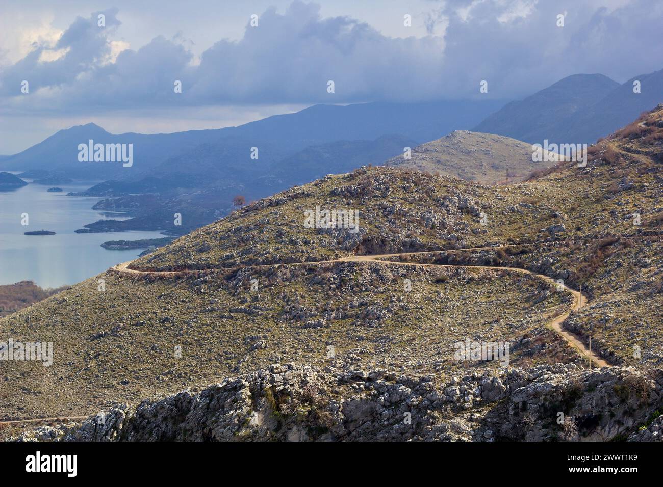 The gravel road on the side of a mountain slope above Lake Skadar, Montenegro. Panoramic road no. 3 Virpazar - Ulcinj near Donji Murici. Stock Photo
