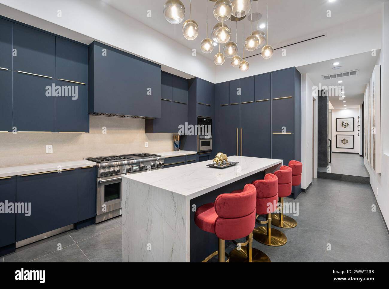 A contemporary kitchen with blue cabinets and a marble countertop Stock ...