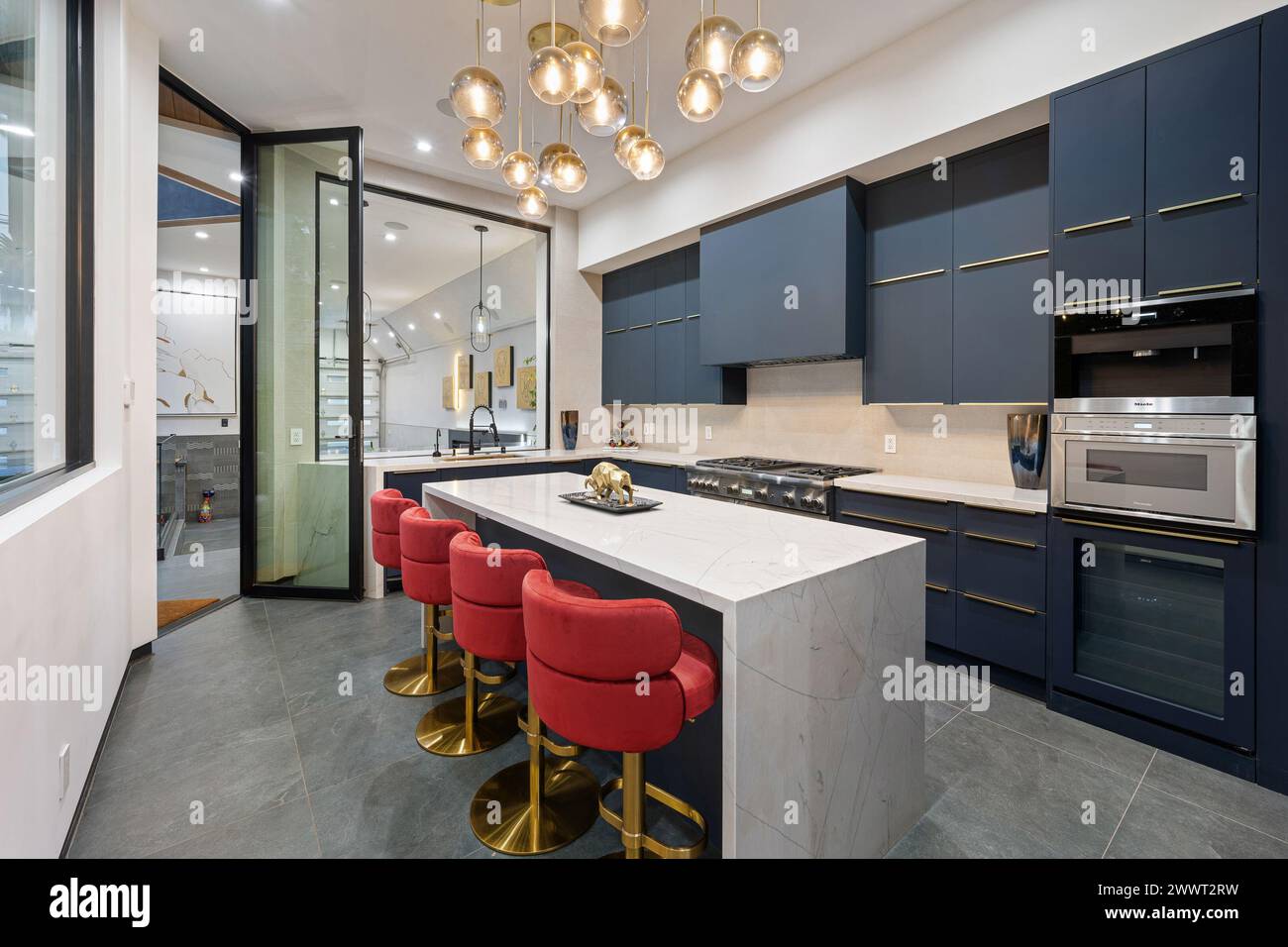 A contemporary kitchen with blue cabinets and a marble countertop Stock ...