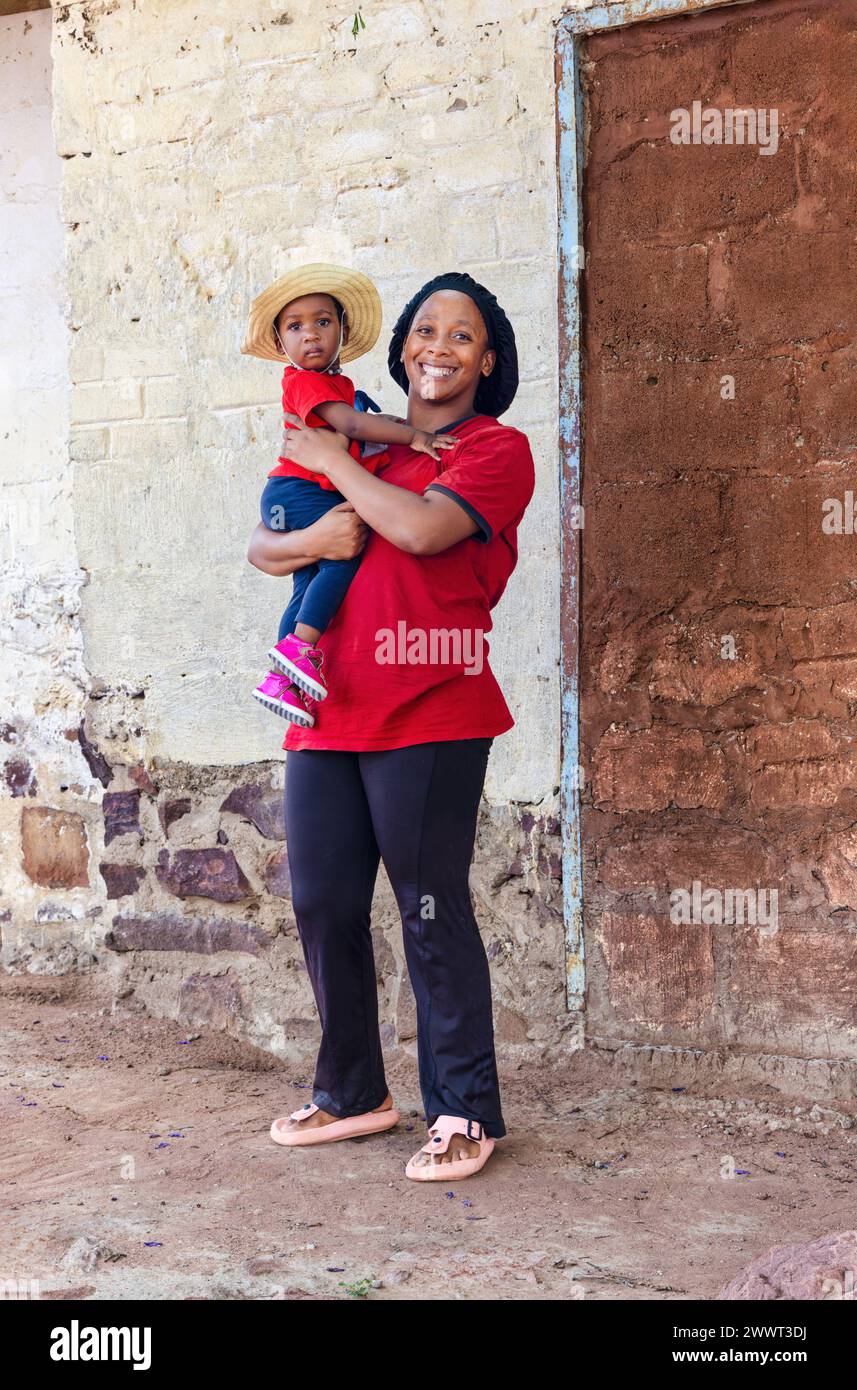 village life, african woman holding her kid standing in front of the house Stock Photo