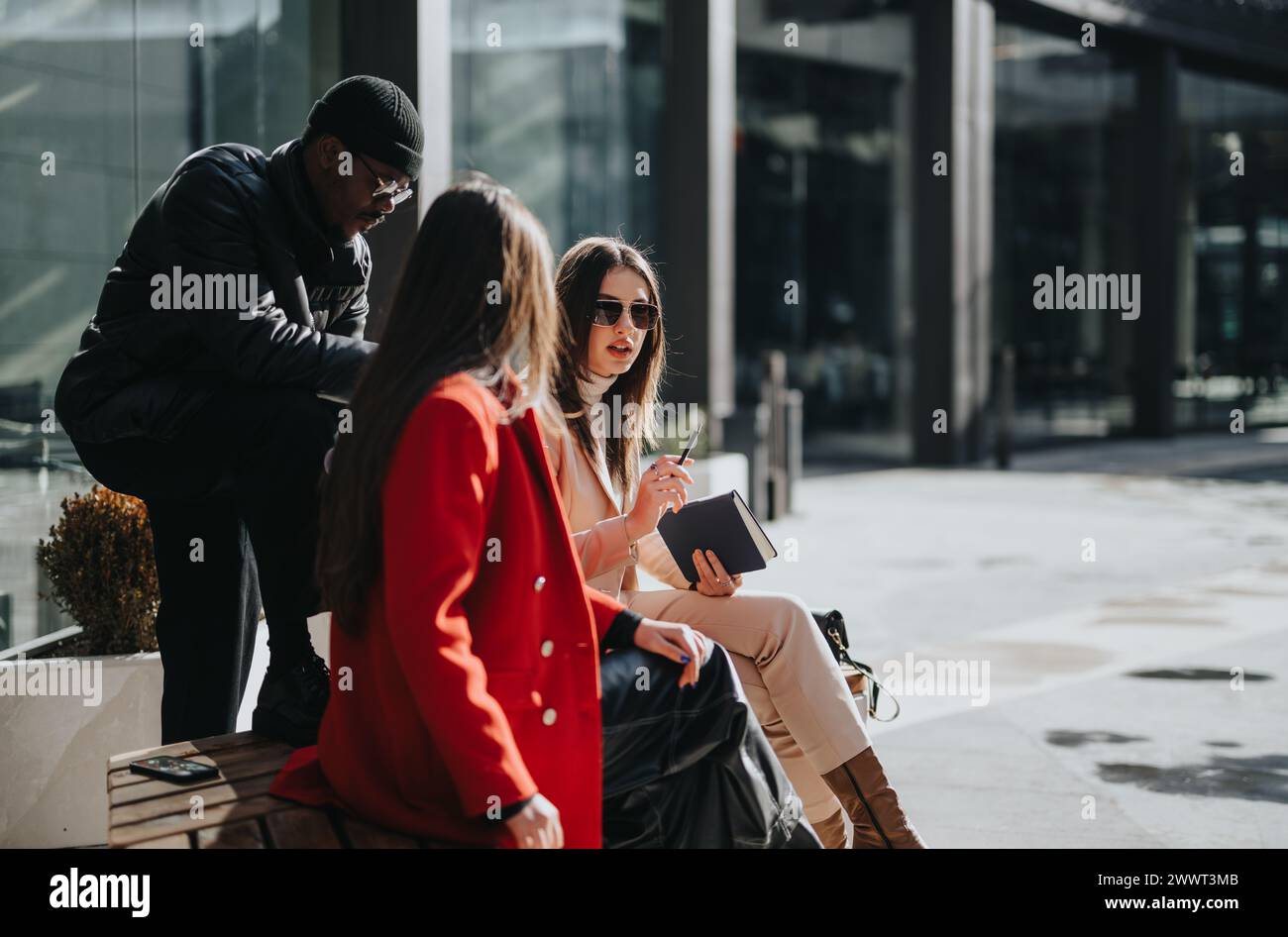 Casual business meeting outdoors with stylish young adults engaged in conversation. Stock Photo