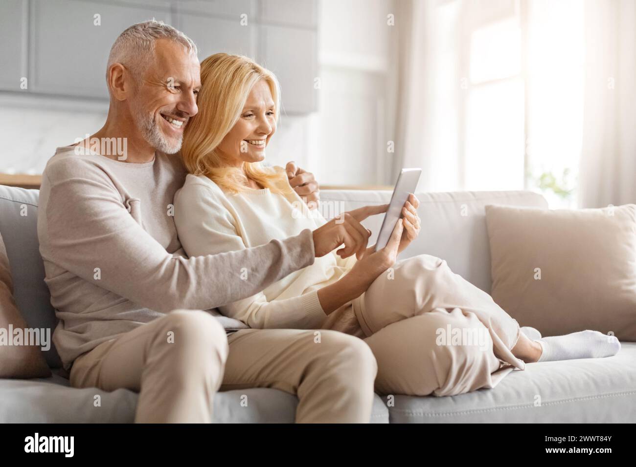 Affectionate couple using tablet on couch Stock Photo