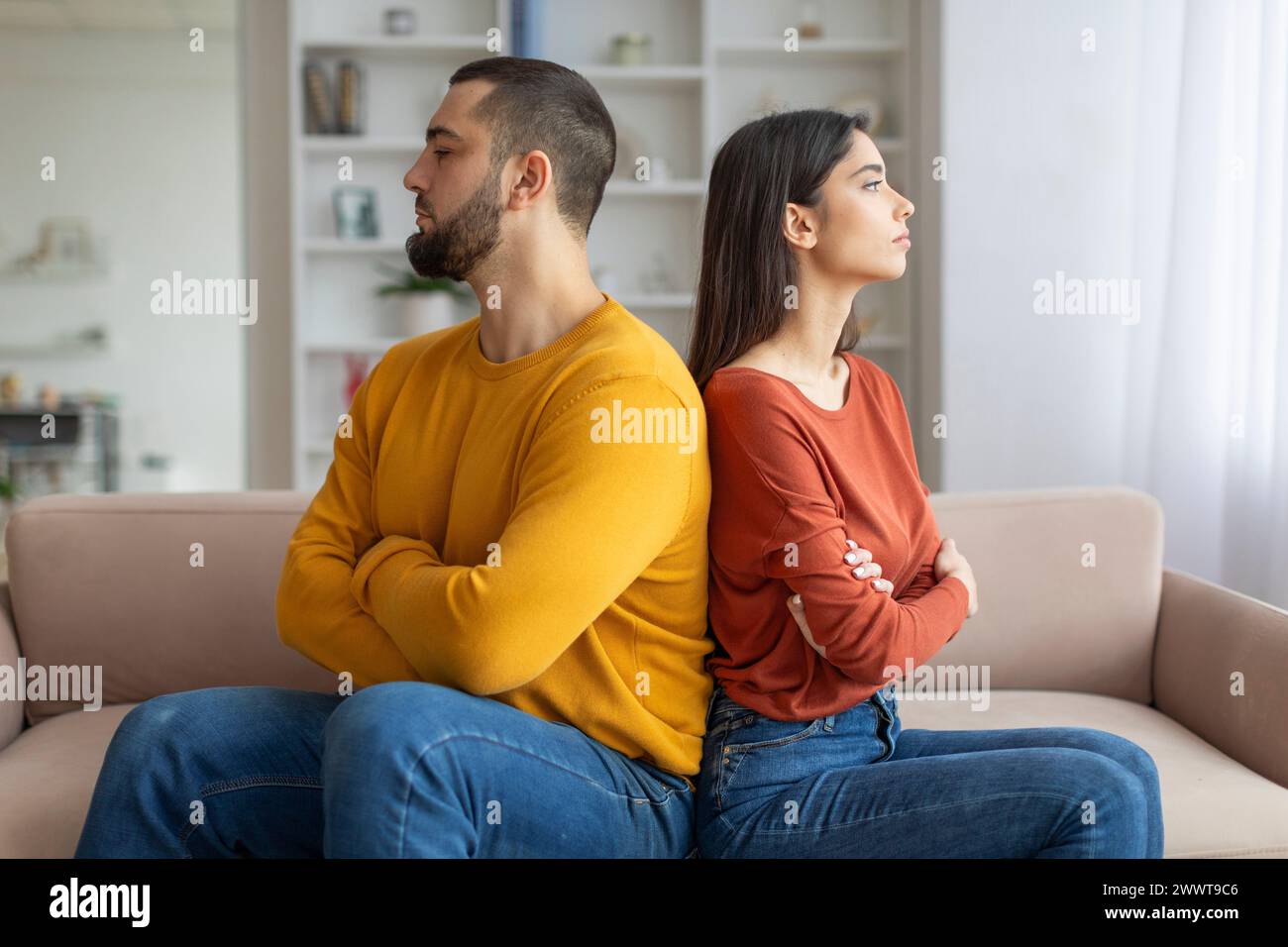 Couple sitting back-to-back looking upset Stock Photo
