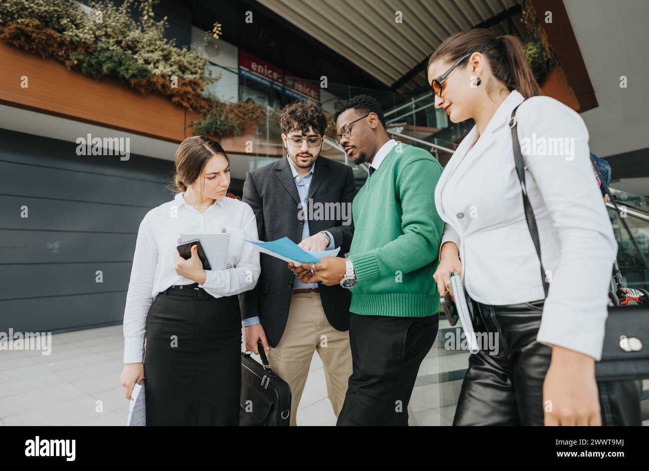 Diverse startup team in casual wear engaging in an outdoor meeting near office Stock Photo