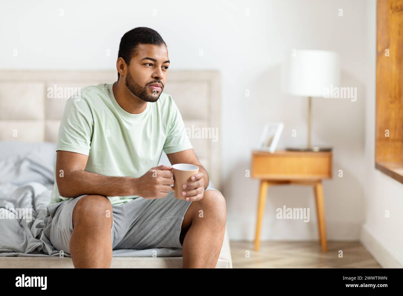 Man sitting with coffee in bedroom Stock Photo
