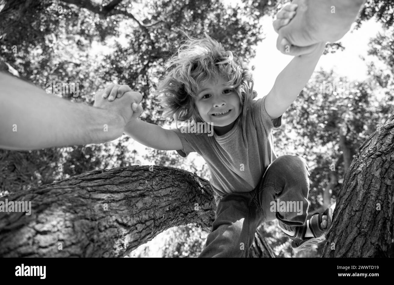 Father helping son to climb tree. Fathers hand. Child protection. Healthy parenting lifestyle. Stock Photo