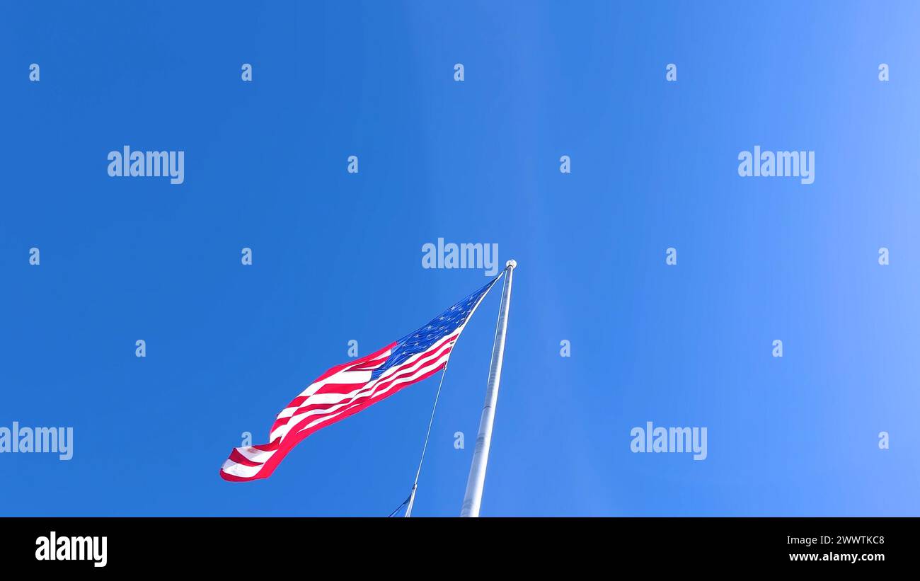 American Flag Waving Proudly Against Clear Blue Sky Stock Photo - Alamy
