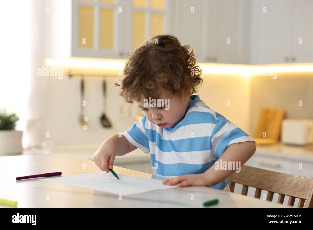 Cute little boy drawing with marker at table in kitchen Stock Photo - Alamy