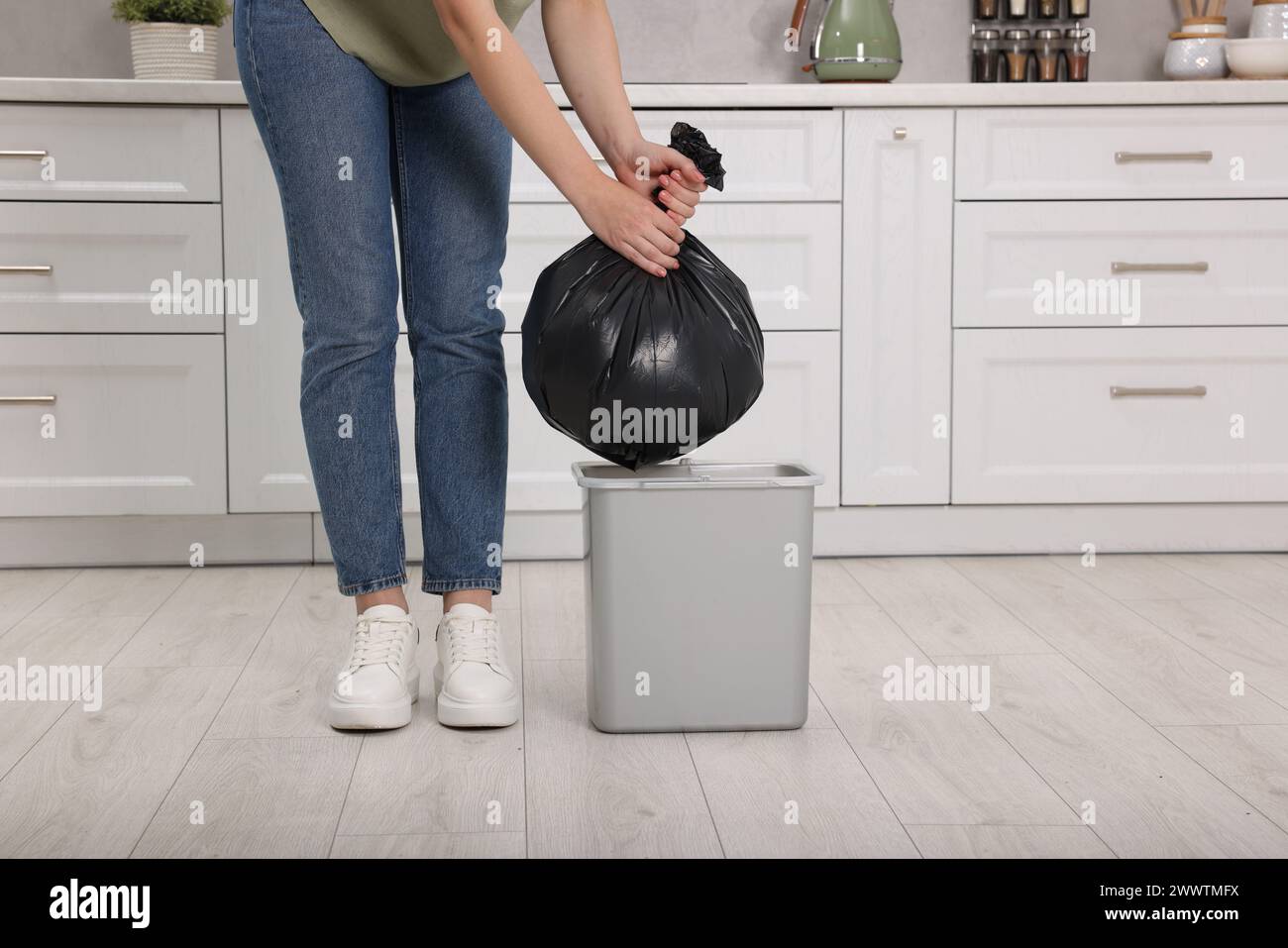 Woman taking garbage bag out of trash bin in kitchen, closeup Stock Photo