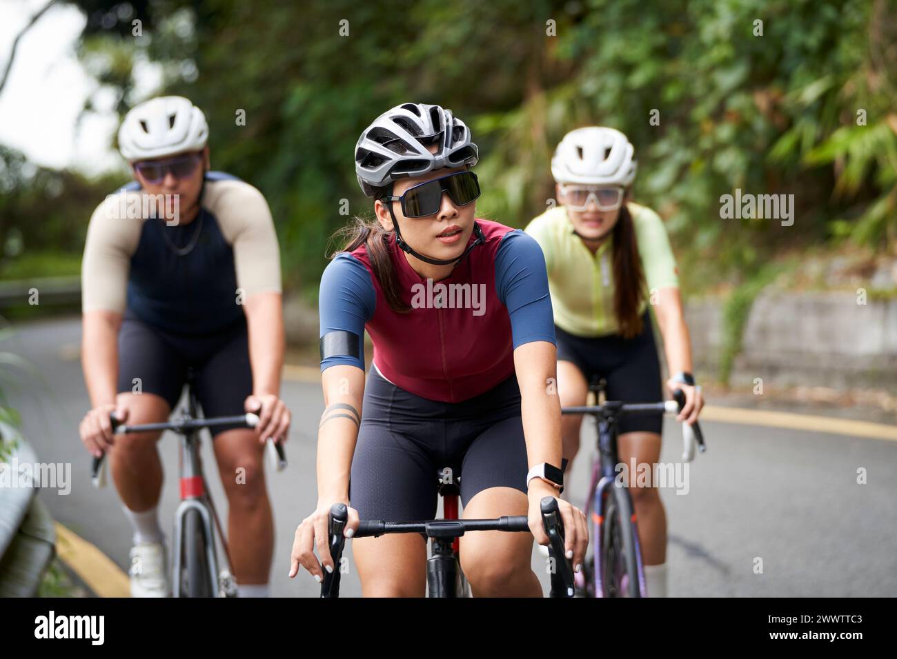 group of three young asian adult cyclists riding bike on rural road Stock Photo