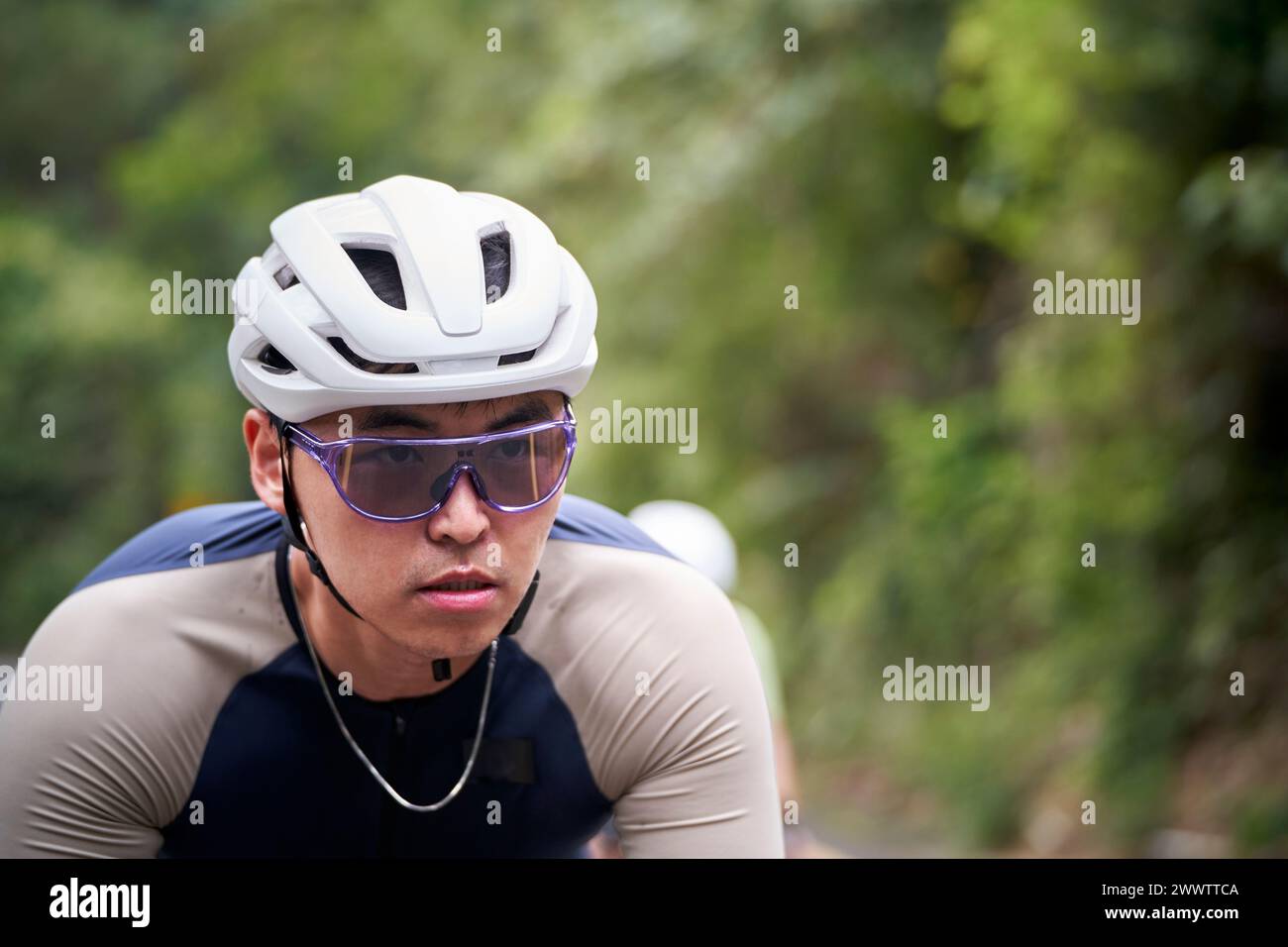 young asian man male cyclist riding bike outdoors on rural road Stock Photo