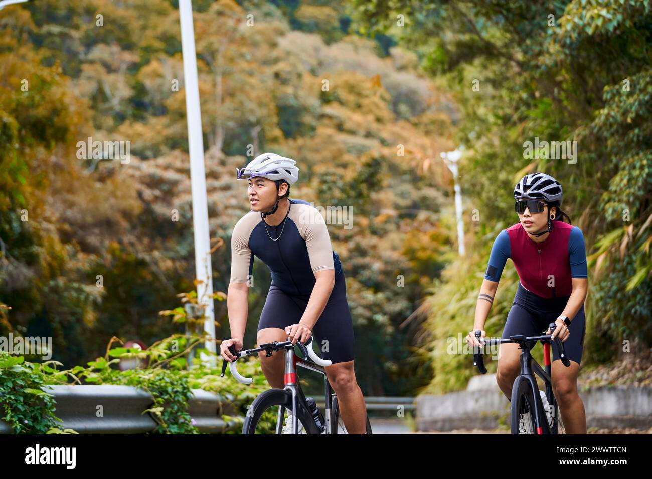 young asian couple cyclists riding bike on rural road Stock Photo