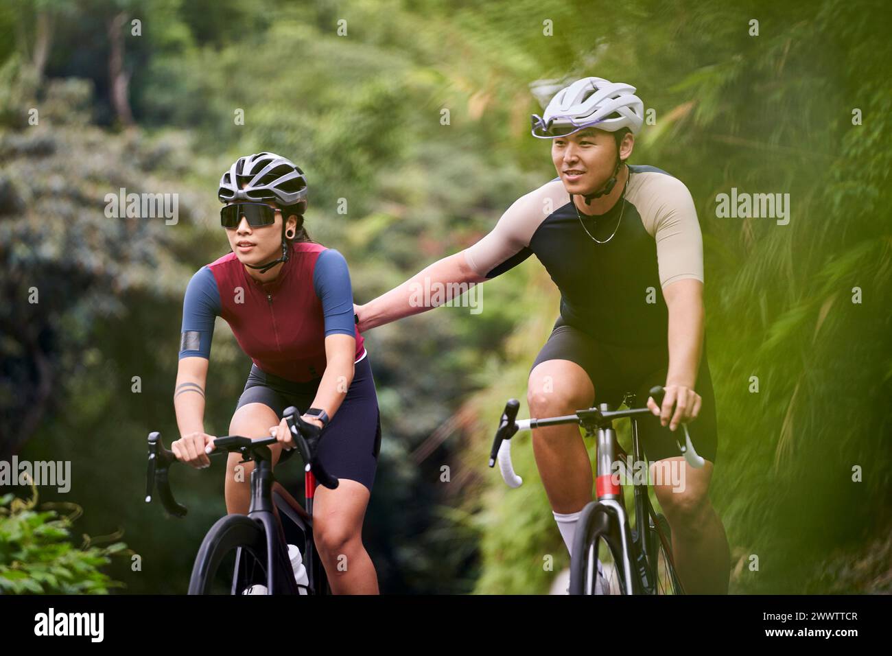 young asian couple cyclists riding bike on rural road Stock Photo