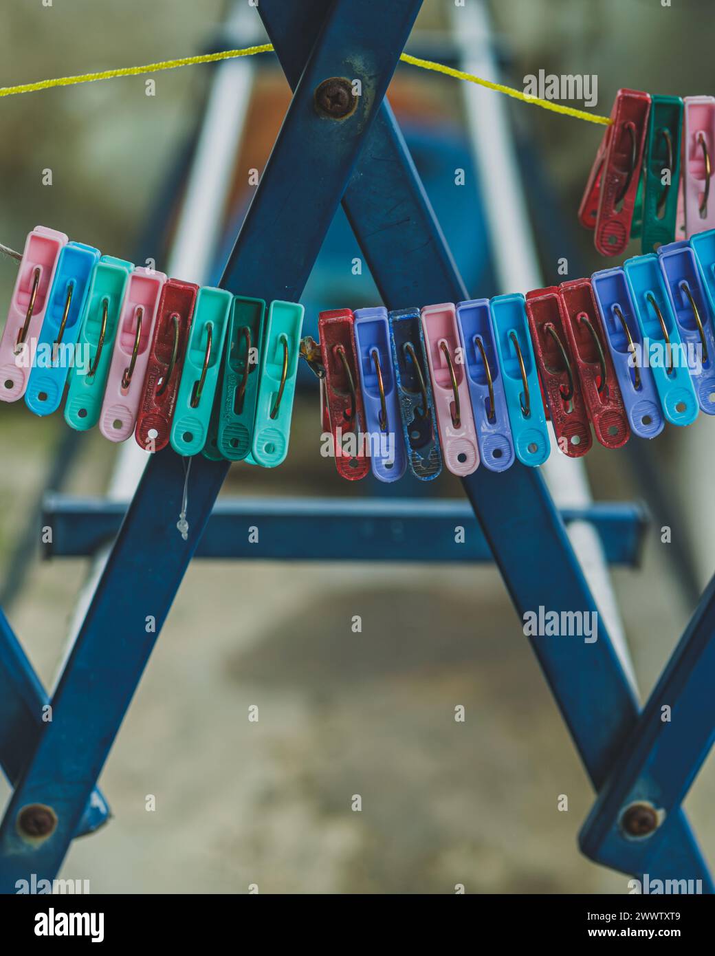 A row of mix old and new clothespins in various color hangs from a taut clothesline. This image is perfect for illustrating laundry day, spring cleani Stock Photo