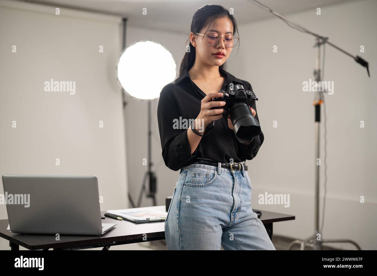 A professional Asian female photographer is focusing on adjusting her ...