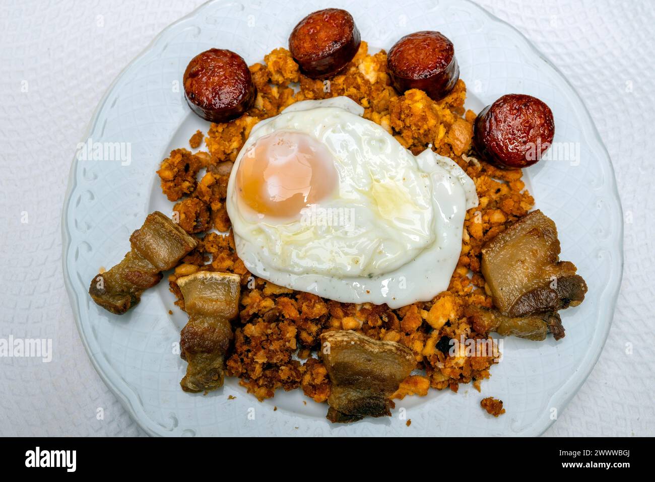 Typical 'migas' stale bread dish served with sausage and fried egg, Guadalupe, Extremadura, Spain Stock Photo