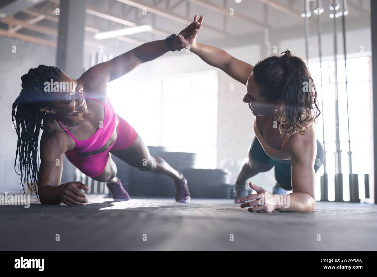 Two fit women are giving high-fives during a workout session in the gym Stock Photo