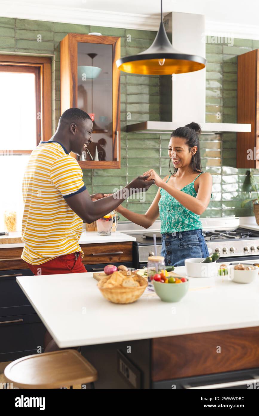 A young African American man and Hispanic woman fist bump in a kitchen Stock Photo