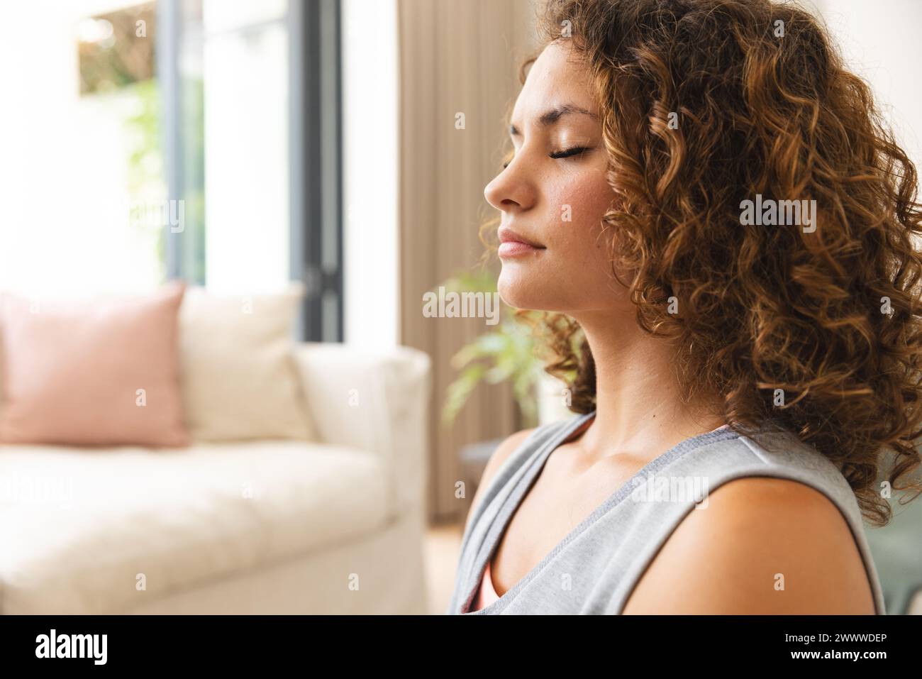 A young Caucasian woman is meditating indoors with copy space at home Stock Photo