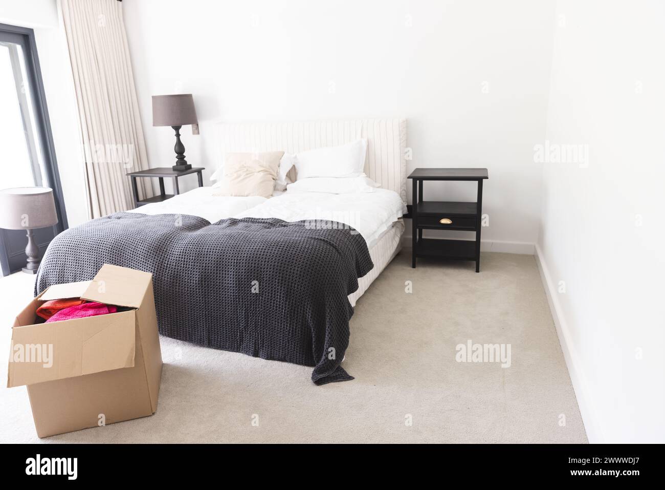 A neatly made bed dominates a bright bedroom with copy space Stock Photo