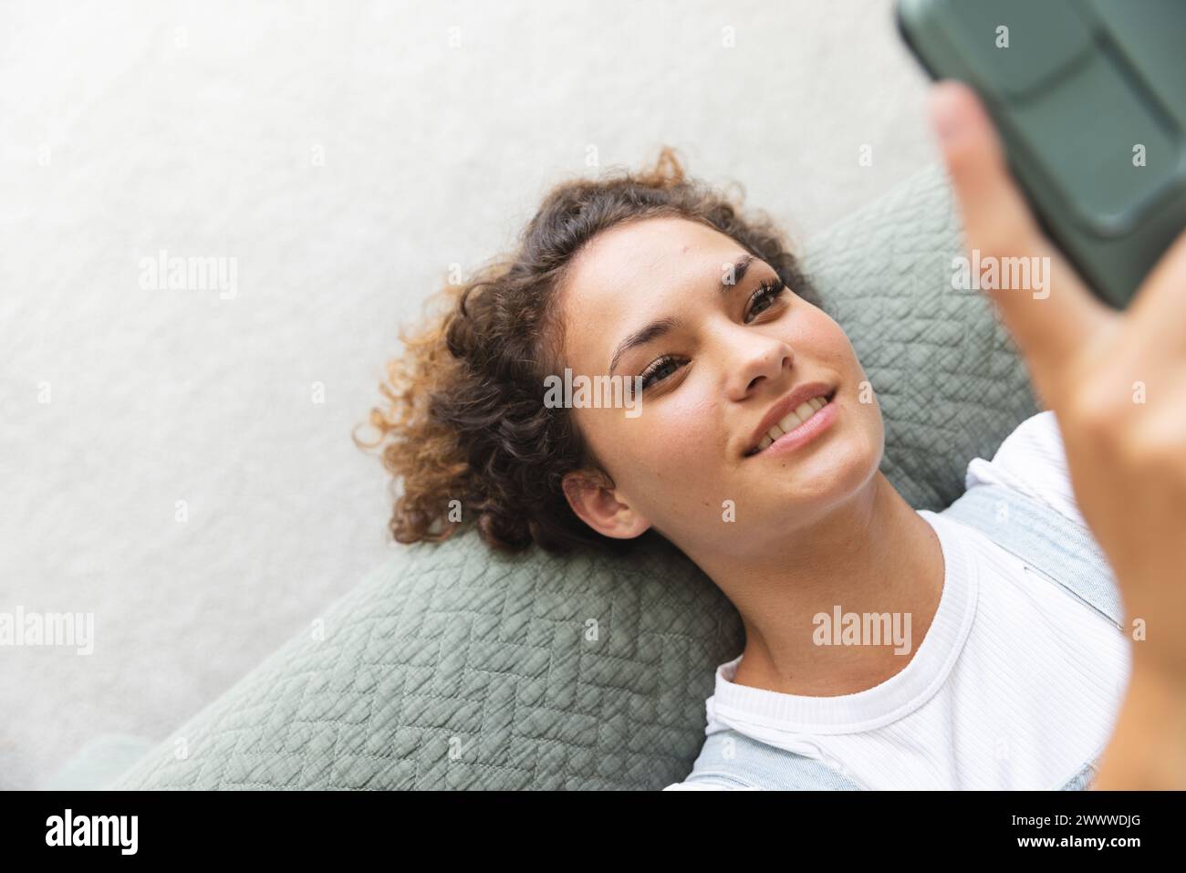 A young Caucasian woman is taking a selfie on bed at home Stock Photo