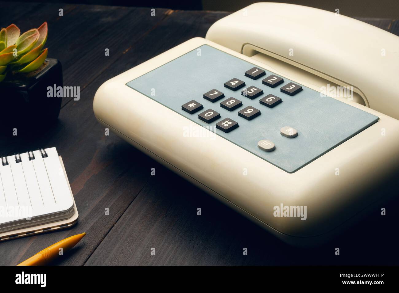 Vintage analog phone on a desktop along with a notepad and a plastic pencil Stock Photo