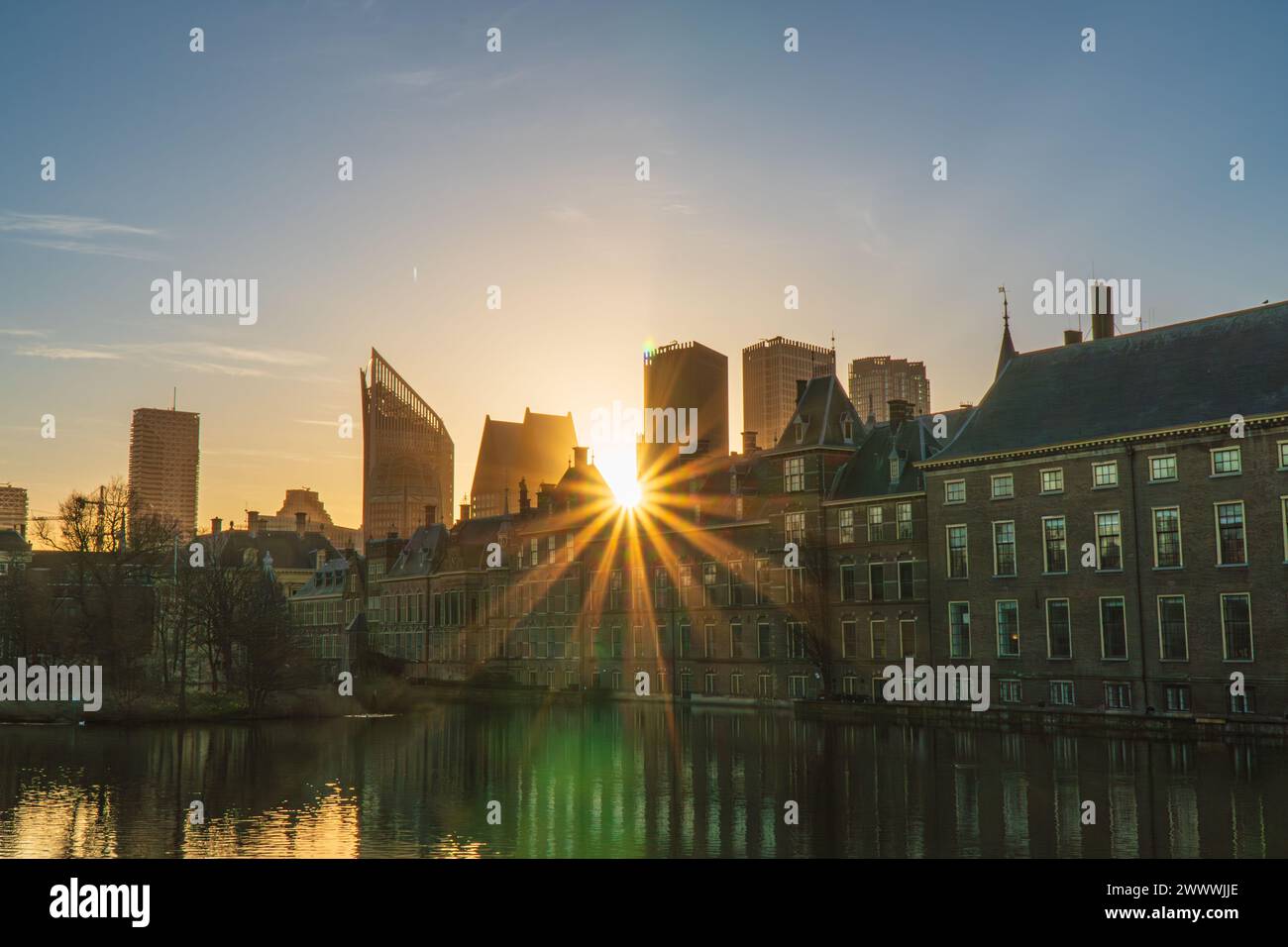 Sun rays piercing through the Binnenhof Castle, Mauritshuis museum and the modern skyline of The Hague, the Netherland. Clear sky, spring. Stock Photo