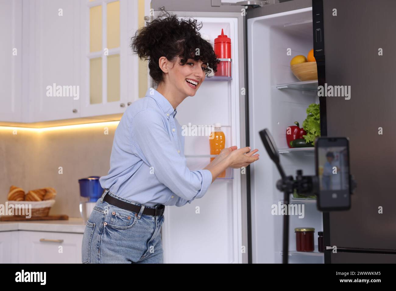 Smiling food blogger explaining something while recording video in kitchen Stock Photo