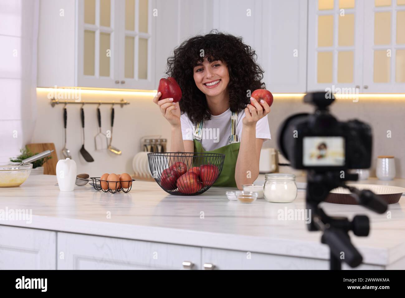Smiling food blogger explaining something while recording video in kitchen Stock Photo