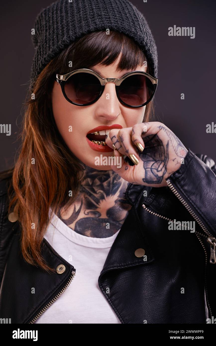 Sunglasses, tattoo or woman in studio for fashion in leather jacket on black background for edgy style. Dark, bold or cool female punk model with ink Stock Photo
