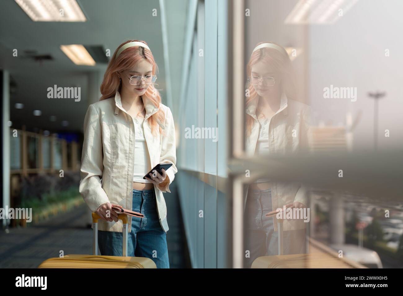 Traveler woman asian in airport and luggage for vacation, smile and talking on the phone check boarding ticket. Female traveler with suitcase Stock Photo