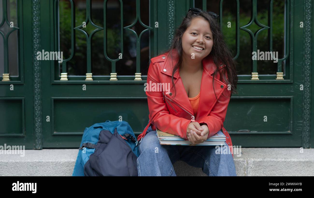 young student sitting on the staircase smiling Stock Photo
