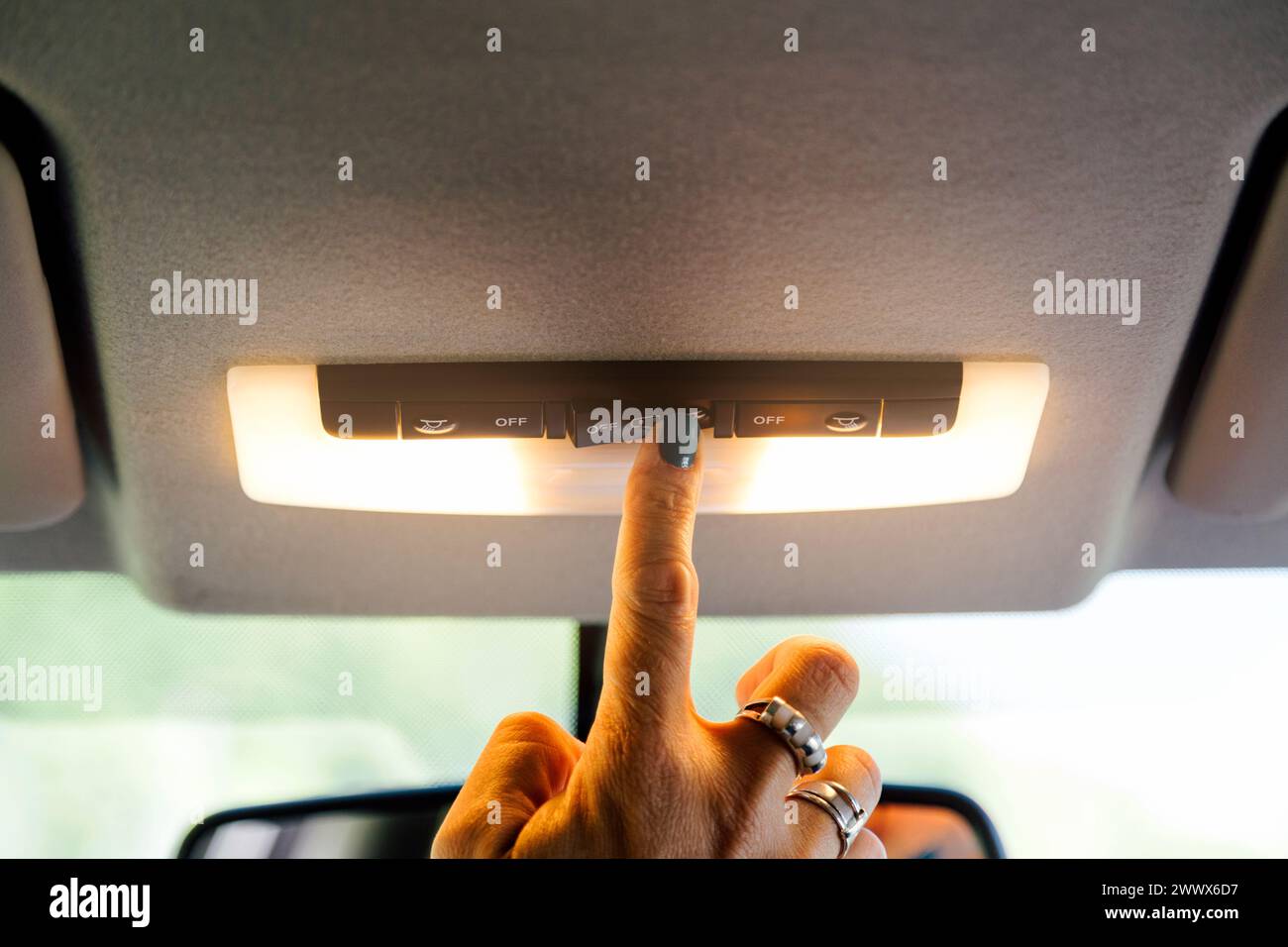 Woman's hand turning on a car interior light. Stock Photo