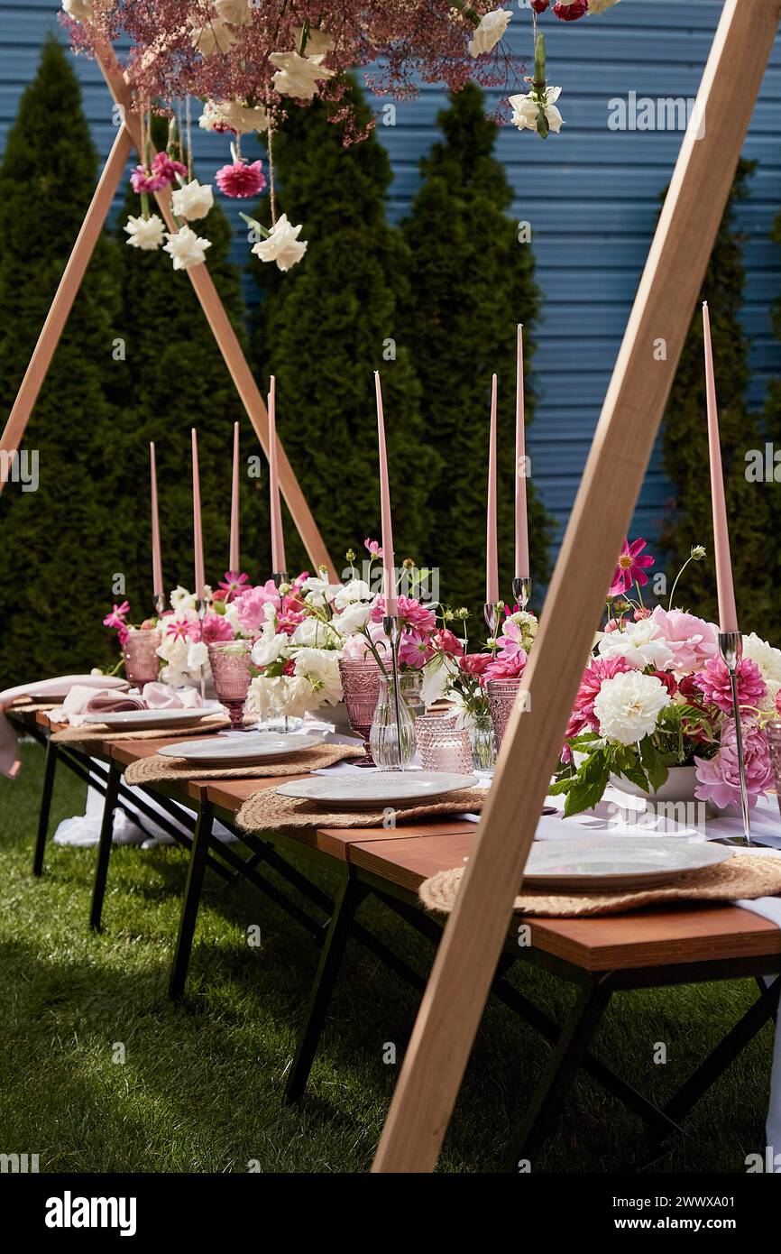 Elegant outdoor table setting with tall pink candles. Romantic dining experience, summer garden picnic Stock Photo