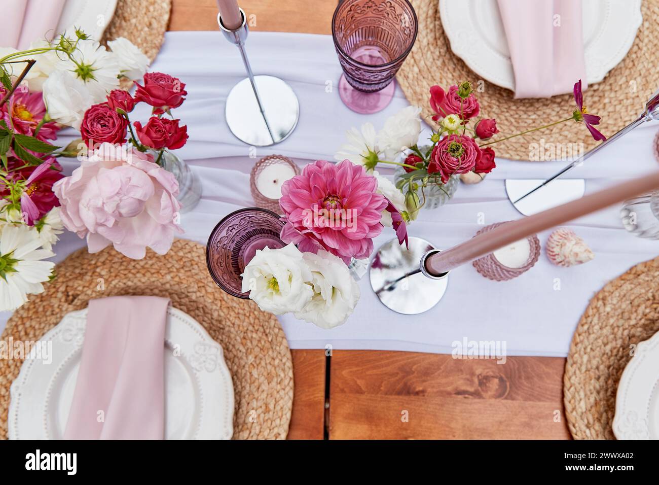 Aesthetics pink womens picnic, served table with flowers bouquets, dishes, shells top view. Stock Photo