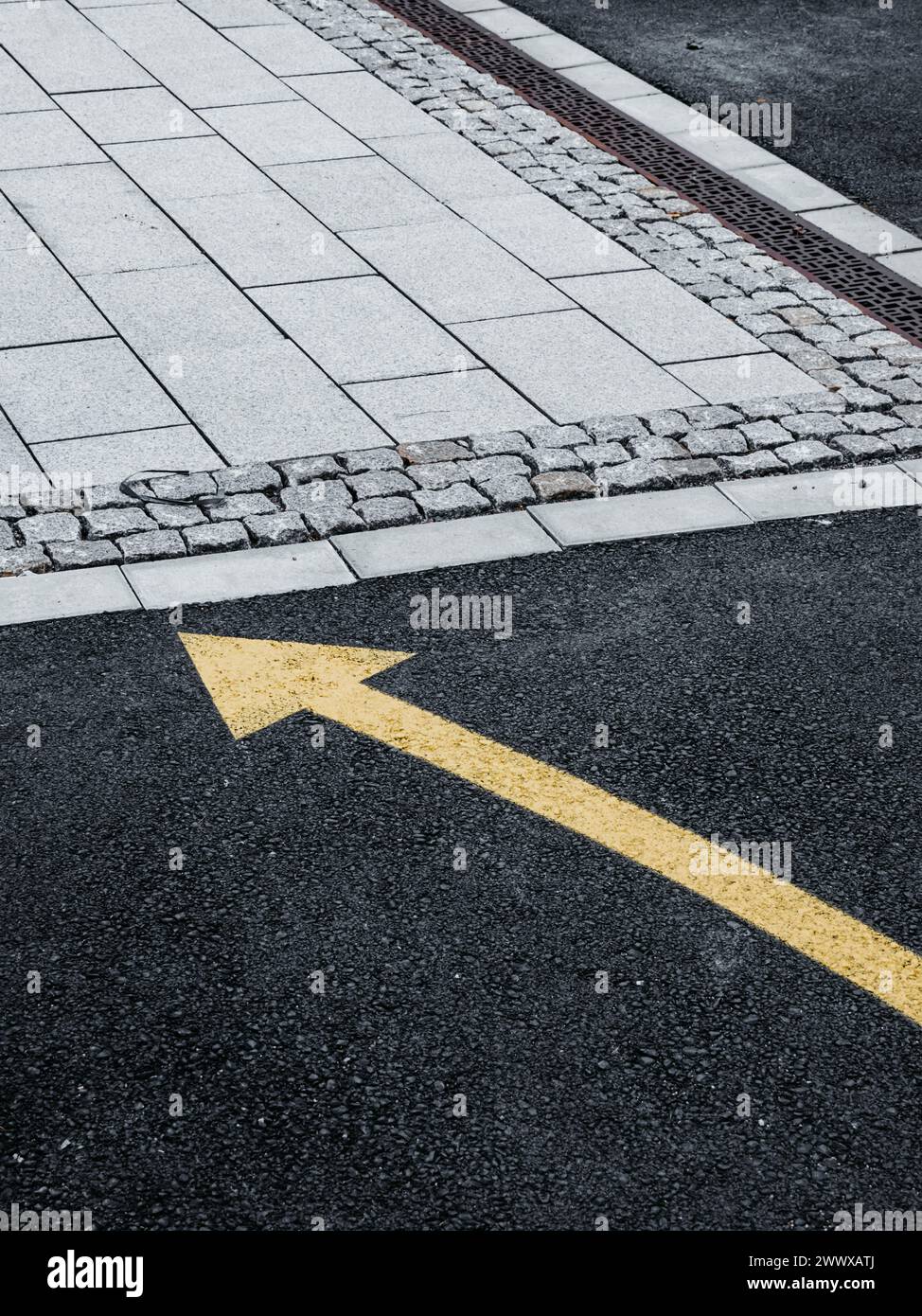 A freshly painted yellow arrow points right on the dark asphalt of a Swedish street, indicating the direction of traffic flow or guiding pedestrians. Stock Photo