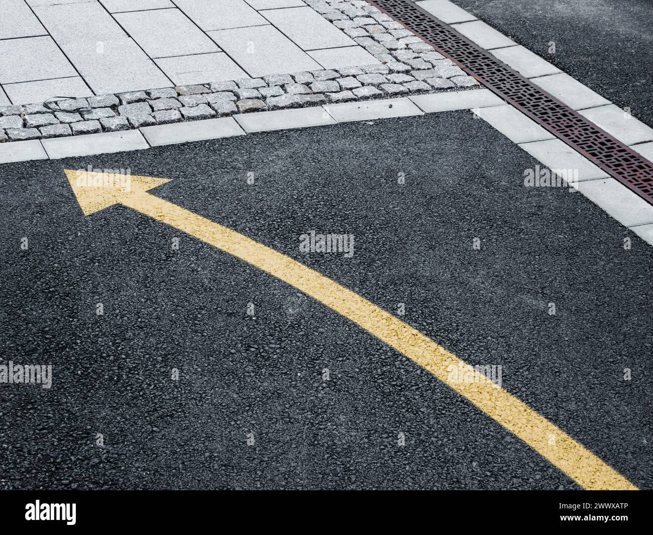 A freshly painted yellow arrow points right on the dark asphalt of a Swedish street, indicating the direction of traffic flow or guiding pedestrians. Stock Photo