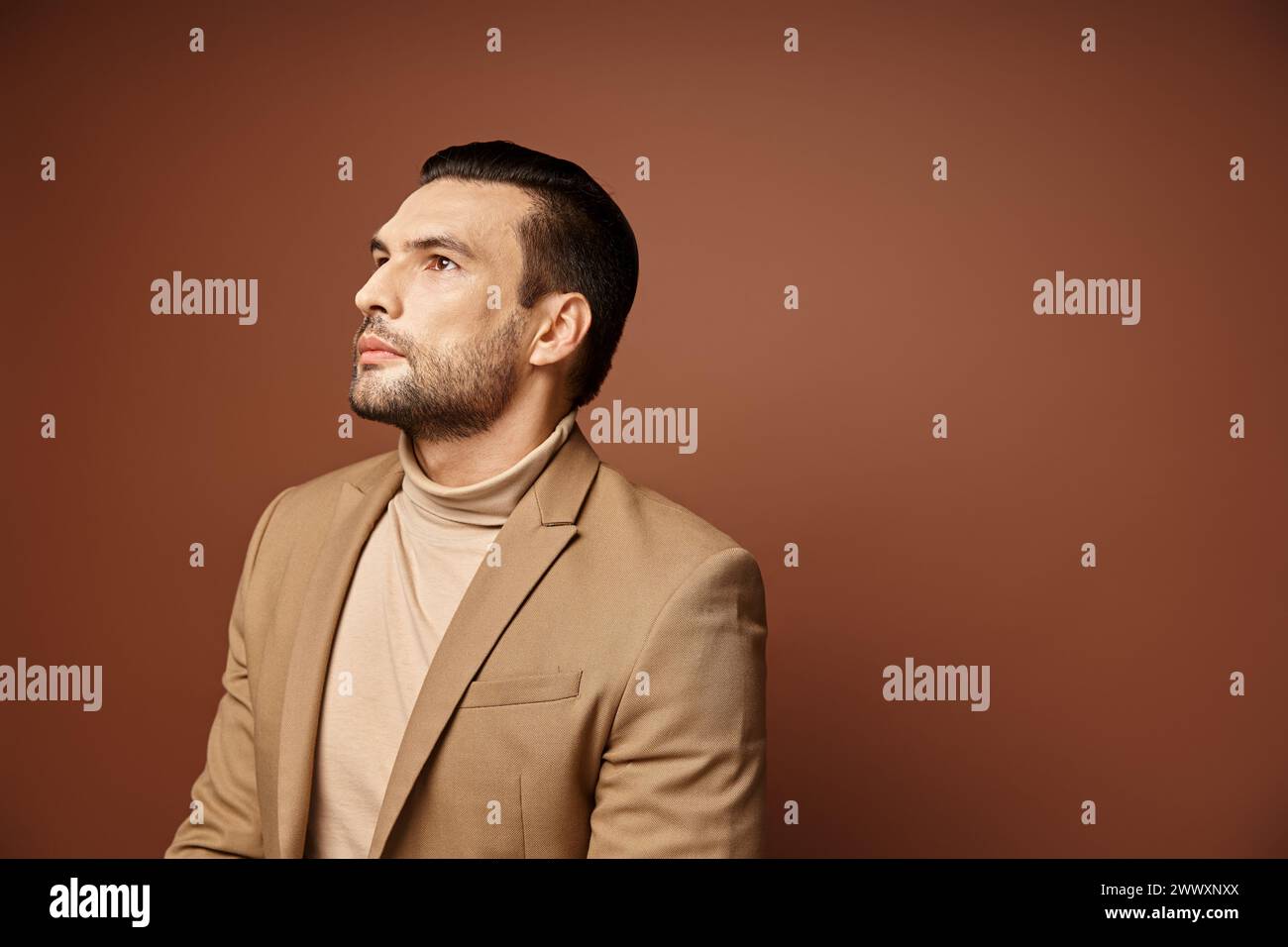 handsome man in elegant attire looking away while thinking on beige