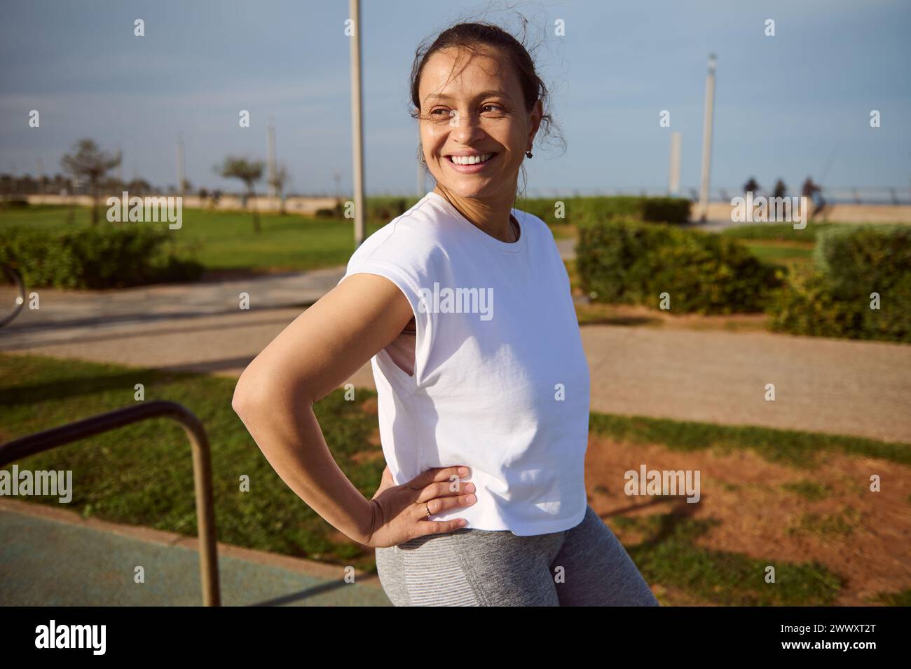 Young happy fitness woman, athlete smiling after running jogging. Authentic portrait of a beautiful sportswoman in white t-shirt, looking away, relaxi Stock Photo