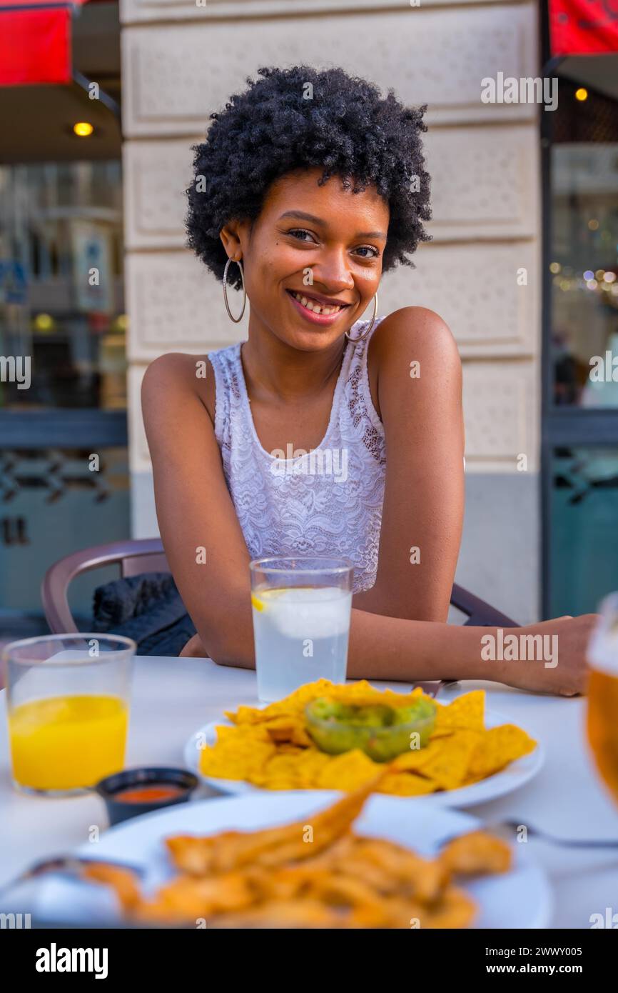 Cute beauty african woman smiling at camera sitting in a fast food