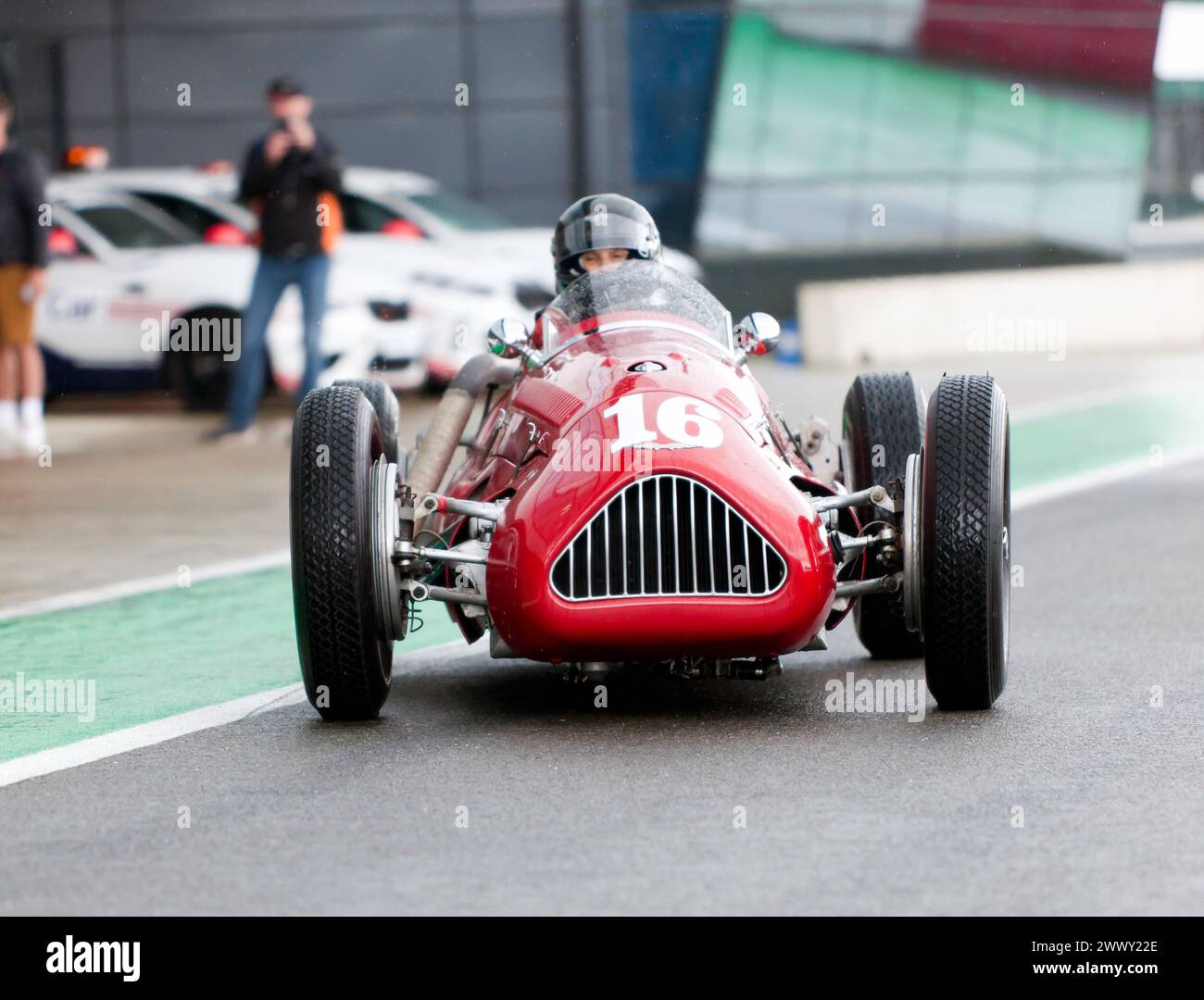 Julia De Baldanza, driving her Red, Alta Grand Prix car, down the International pit lane, before the start of the HGPCA pre '66 Grand prix Cars Race. Stock Photo