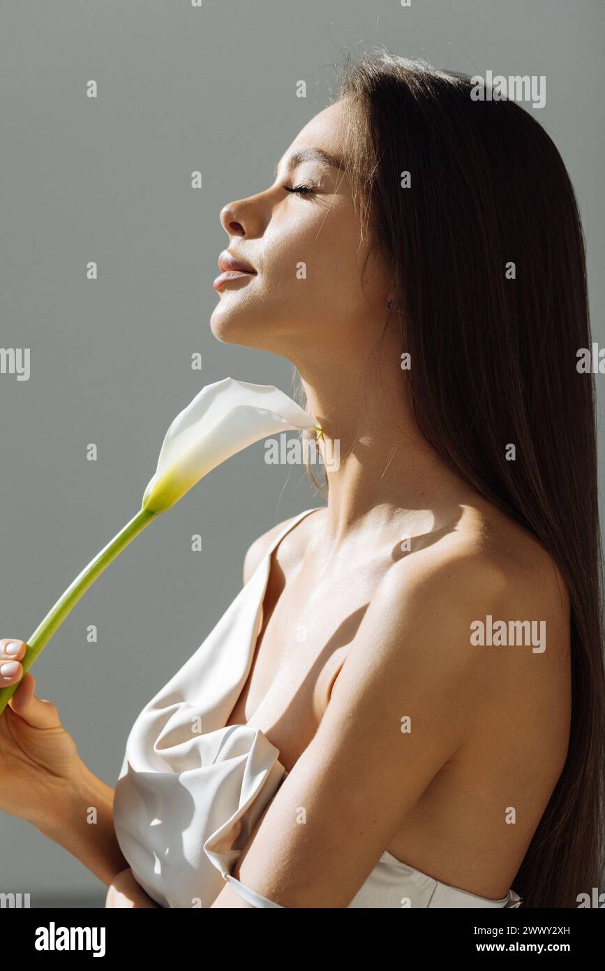 Beauty face of the young beautiful woman with flower. Female touching skin. Girl on white background Stock Photo