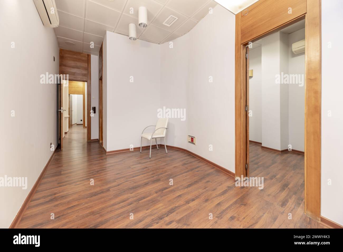 An empty office with curved walls, reddish parquet floors and technical ceilings Stock Photo