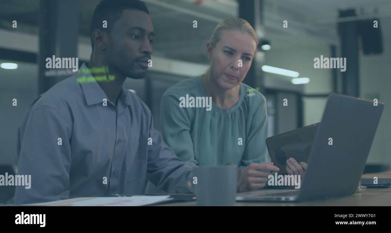 Image of data processing over diverse colleagues using laptop and tablet in office. Business, communication, technology, computing and digital interfa Stock Photo