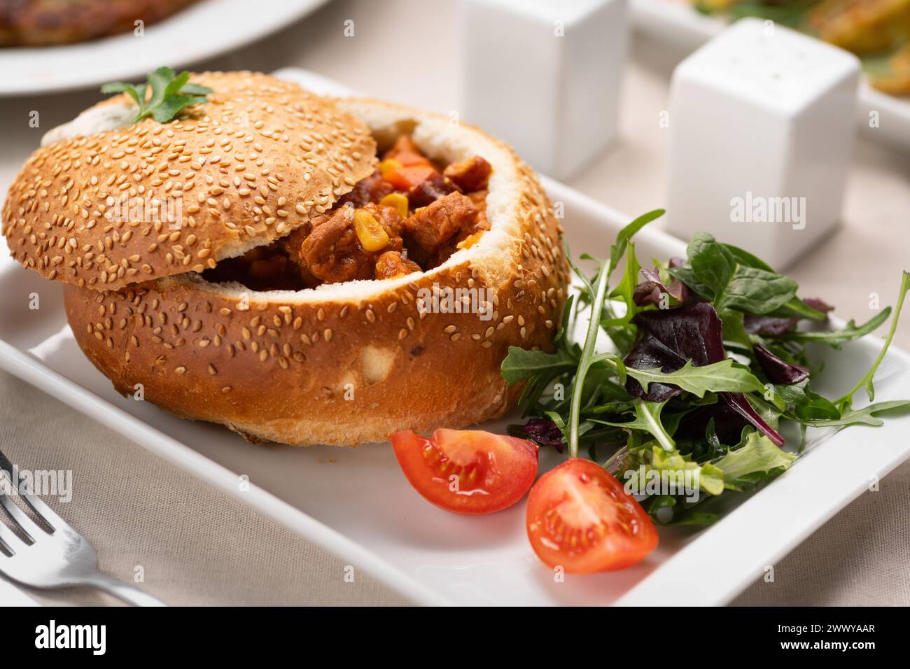 meat goulash in a loaf of bread served on a white plate in a restaurant. Traditional Hungarian cuisine Stock Photo