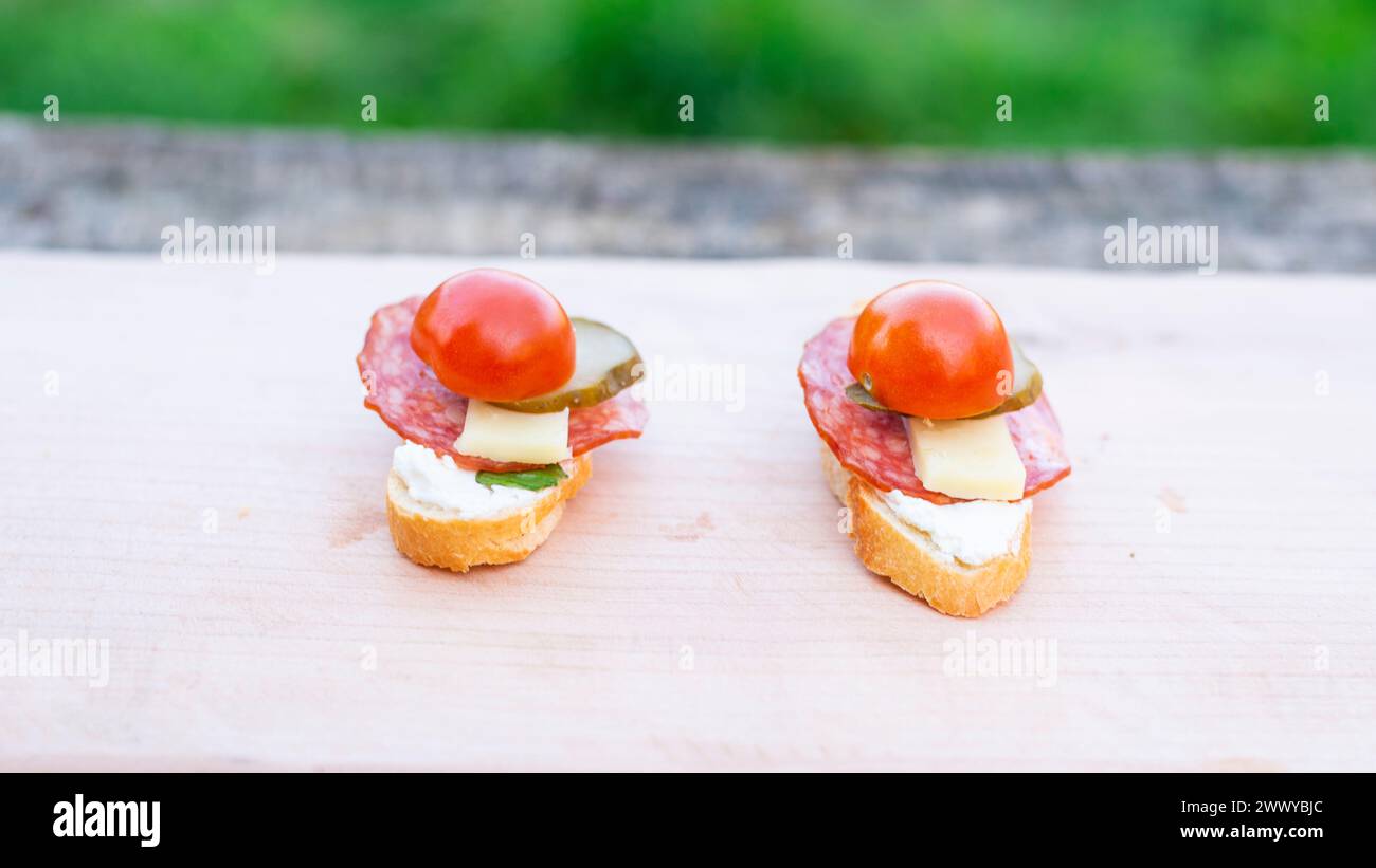 Finger food, bruschettas with salad, cheese , bacon , cucumber and cherry tomato on wooden table. Stock Photo