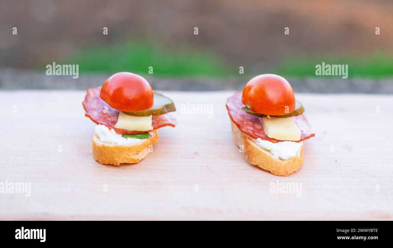 Finger food, bruschettas with salad, cheese , bacon , cucumber and cherry tomato on wooden table. Stock Photo