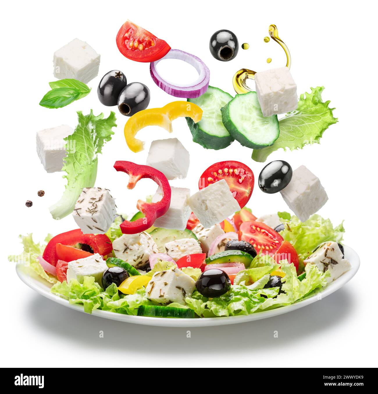 Fresh vegetables and feta cheese falling down into the white plate isolated. File contains clipping paths. Stock Photo