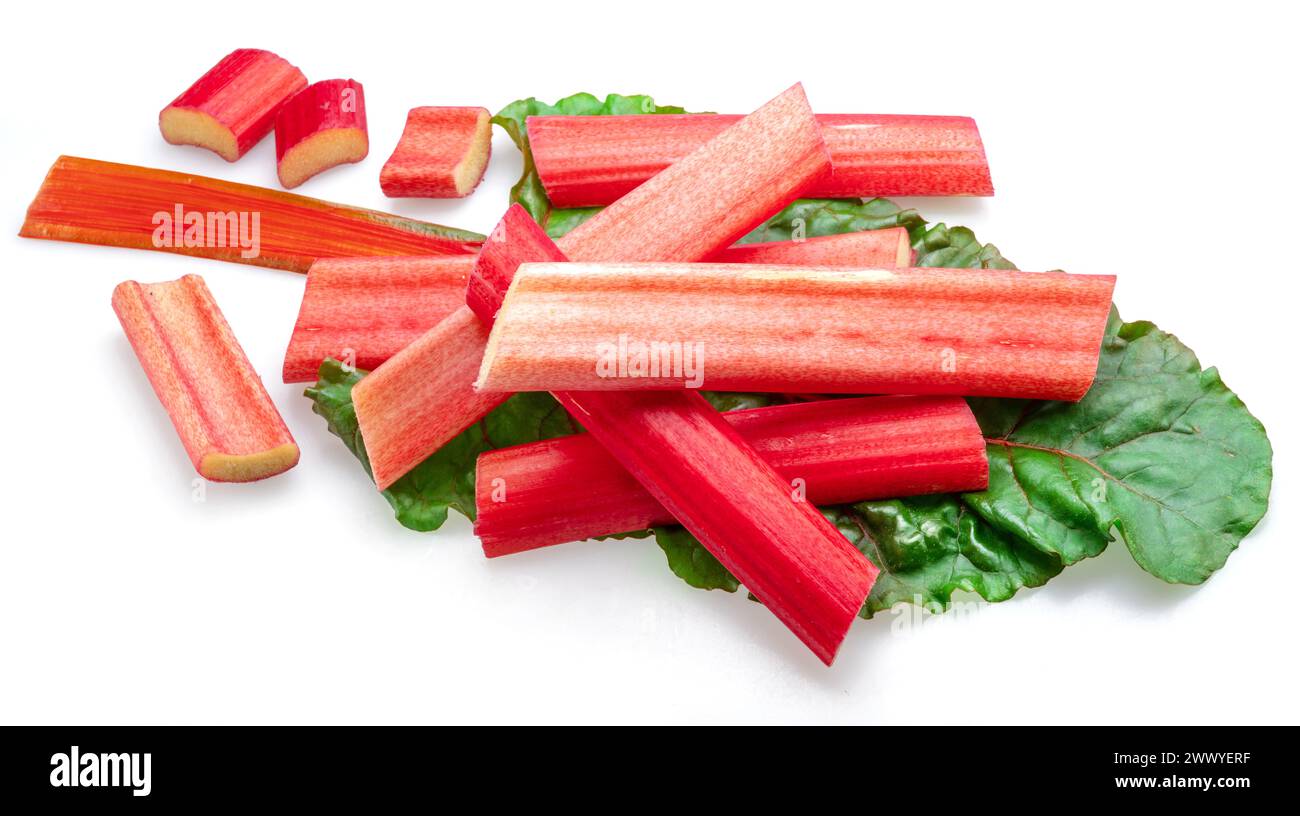 Red rhubarb stems' cuts over rhubarb leaves isolated on white background. Stock Photo